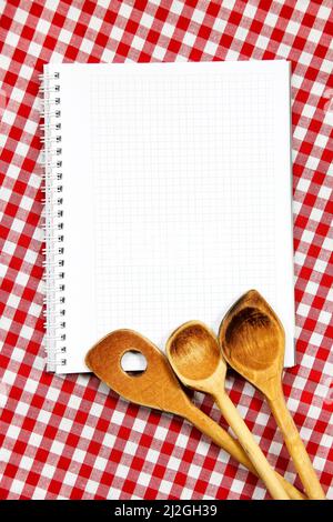 Wooden cooking untencil and blank notice book for writing recipe against red and white gingham table clothing background Stock Photo
