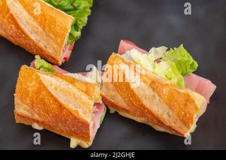 delicious ham sandwich with cheese and lettuce, on a black plate, cooked in a restaurant Stock Photo