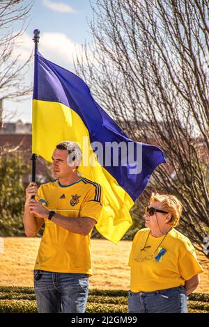 2022 03 05 Tulsa, OK USA - Young man holding Ukrainian flag and older woman in blue jeans and yellow tee-shirts at rally to support Ukraine Stock Photo