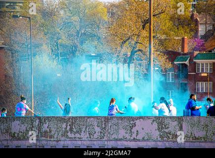 April 6 2019 Tulsa USA - Holi - Color Run in Tulsa USA - Runners are squirted with colored powder on bridge with houses and trees behind them Stock Photo