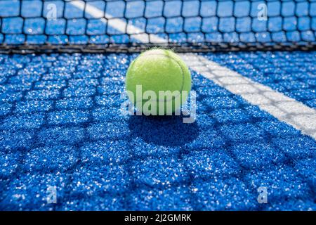 ball in the shade of the net on a blue paddle tennis court Stock Photo