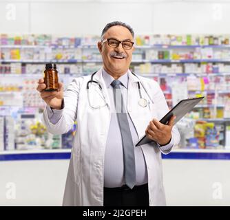 Smiling mature chemist holding a bottle of pills in a pharmacy Stock Photo