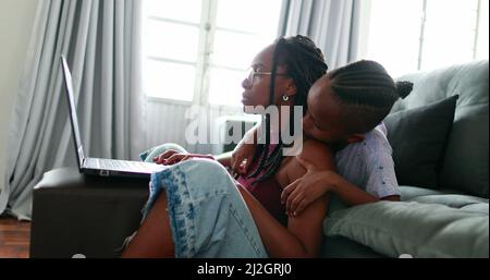 Black African parent working from home using laptop computer. Mother multi-tasking Stock Photo
