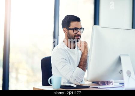 Pleased with his progress. Cropped shot of a young man working in his office. Stock Photo