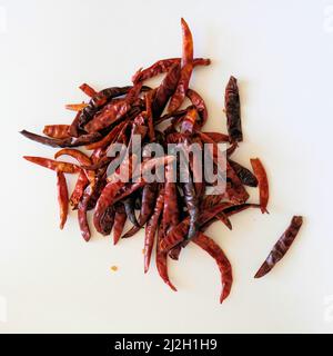 Roasted chile de arbol peppers on a white surface; capsicum annum variety; Mexican pepper used for cooking and making salsa and sauces. Stock Photo