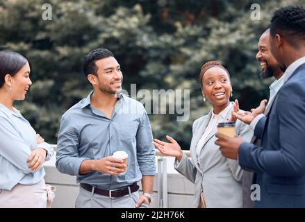 I couldnt believe she said that. Shot of a group of businesspeople outside having coffee and conversation. Stock Photo