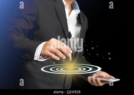 A young entrepreneur uses darts embroidered on tablet abstracts to set goals for successful investments in his corporate business in planning for the Stock Photo