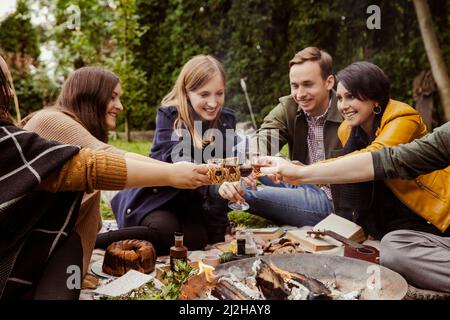 Group of friends toasting around fire pit in garden Stock Photo
