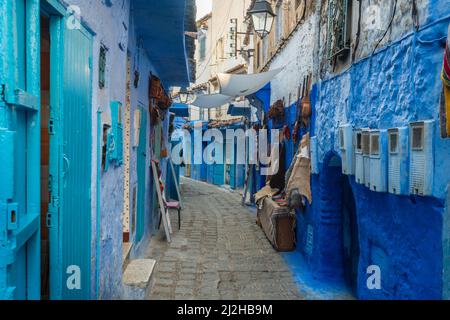 Morocco, Chefchaouen, Narrow alley and souvenirs for sale at blue buildings Stock Photo