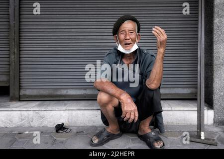 Thailand senior man, happy and smiling. squatting on the pavement. Southeast Asia Stock Photo