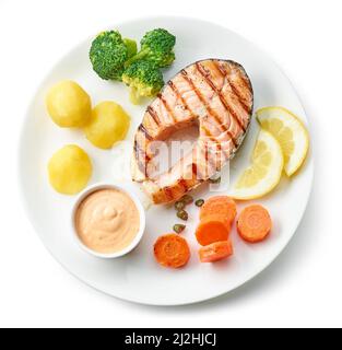 plate of grilled salmon steak and vegetables isolated on white background, top view Stock Photo