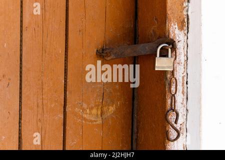 Padlock on an old brown wooden door with cracked paint. Close-up. High quality photo Stock Photo