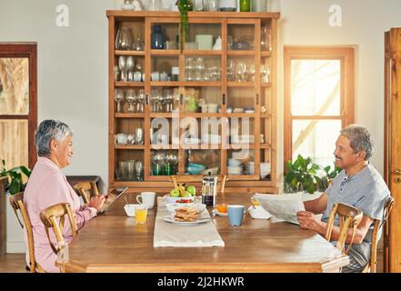 Can you please pass the salt. Shot of a cheerful elderly couple having breakfast together around a table at home during the day. Stock Photo
