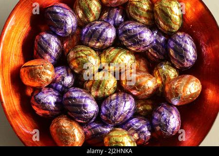multi-colored wrapped chocolate easter eggs in orange bowl Stock Photo