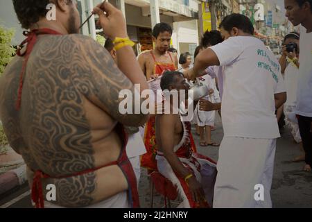 Men assist a Ma Song, a Chinese Taoism devotee performing cheek slashing, during a preparation of celebration popularly known as the Nine Emperor Gods Festival in Nakhon Si Thammarat, Thailand. Southern Thailand in Malay Peninsula, also known as 'Ligor' by Srivijaya scholars) was a political centre of Srivijaya. When describing Chenla kingdom (Cambodia), Chau Ju-kua (Zhao Rugua)—a 13th century Chinese commissioner for international trade who worked for Song Dynasty—mentioned that 'this country (Chenla) confines to the south on Kia-lo-hi (Ligor), a dependency of Srivijaya.' Stock Photo