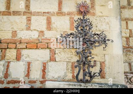 Forged steel cross, leaning against the church wall in the courtyard. Serbian Orthodox Church in Sremska Kamenica - Church of the Nativity of the Most Stock Photo