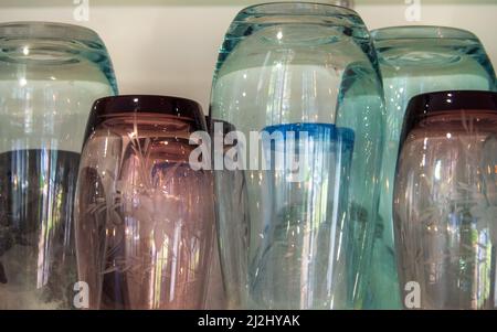 Drinking glasses, some new some vintage with engraved design, green, purple and blue, shiny, pretty display on kitchen shelf in the home, water glass Stock Photo