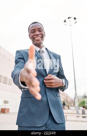 portrait of african american smiling young businessman looking at camera and extending arm for handshake. Deal concept and welcoming Stock Photo