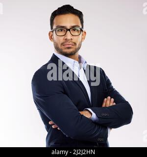 A successful entrepreneur believes in his abilities. Studio portrait of a confident young businessman standing with his arms crossed against a white Stock Photo