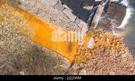 Aerial view of orange iron oxide staining in stream entering River Neath at Abergarwed. The source is water discharging from an abandoned coal mine. Stock Photo