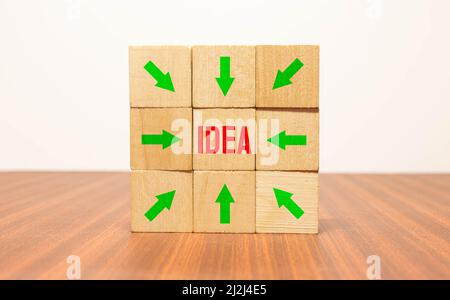 Cubes and dice with arrow and bow icon showing the word idea - idee, metaphor goal or target on wooden background. Stock Photo