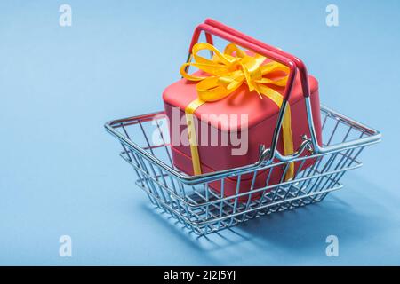 Box tied with a bow in a basket on a blue background. Stock Photo