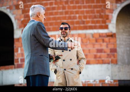 Amazing two senior businessmen are talking about the company new plans while smiling Stock Photo