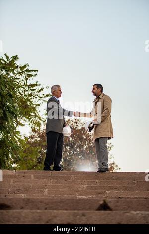 Two senior businessmen are shaking their hands about the deal Stock Photo