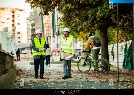 Two construction workers are walking together while talking to each other Stock Photo