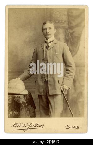Original Edwardian era cabinet card of handsome British military gentleman of the British Raj, wearing a suit and tie and pith hat. From studio of Albert Edward Jeakins, Simla (Shimla) in India. Simla was once the Summer capital of British India, dated 8 March 1904. Stock Photo