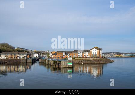 Penarth (old harbour) Marina leading into Cardiff Bay with properties reflected in the still water on a sunny April day Stock Photo