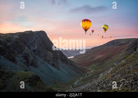 Digital composite image of hot air balloons over Epic landscape image of view down Honister Pass to Buttermere from Dale Head in Lake District during Stock Photo