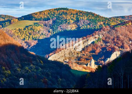Autumn mountain landscape with forest and long shadows. The sun illuminated valley and hill with, beautiful colorful trees.  Vrsatec, Slovakia. Stock Photo