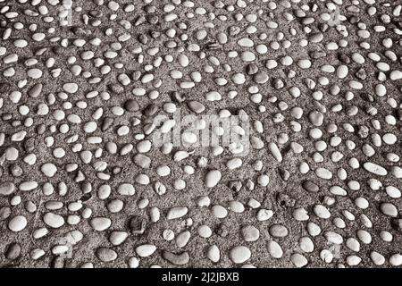 Decorative background of small pebbles in concrete. Pavement made of pebbles and concrete mixture. Texture of pebbles for poster, branding, calendar Stock Photo