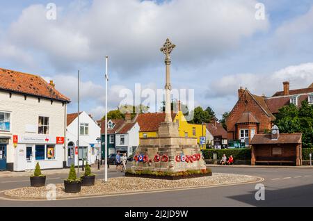 The war memorial with poppy wreaths in the market square of Holt, a small historic Georgian market town in north Norfolk, Gresham's School behind Stock Photo