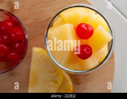 Cubes of pineapple in a glass with two cherries on top, Stock Photo