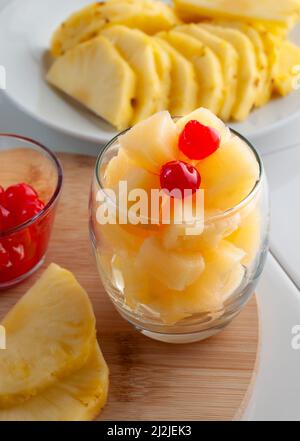 Cubes of pineapple in a glass with two cherries on top, Stock Photo
