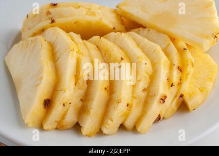 Pineapple slices on a white plate as part of healthy foods concepts. Macro photohgraphy, side view. Stock Photo