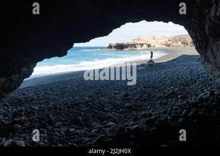 Silhouette of person photographing the sea with smartphone view from a sea cave, Ajuy, Fuerteventura, Canary Islands, Spain Stock Photo