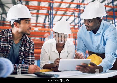 Here comes another top quality design. Shot of a group of builders having a meeting at a construction site. Stock Photo