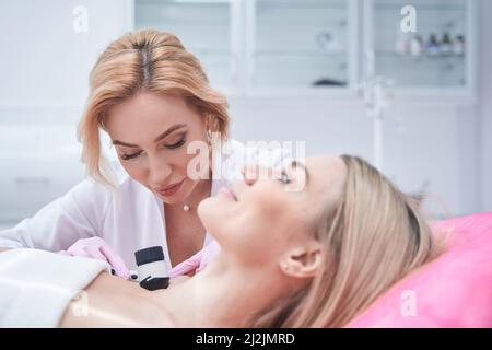 Focused doctor in nitrile gloves performing dermoscopy Stock Photo