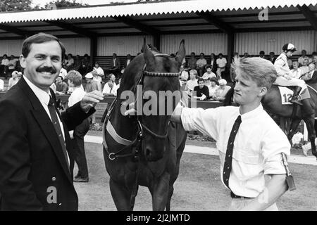 Redcar Racecourse is a thoroughbred horse racing venue located in Redcar, North Yorkshire. Evening Gazette managing director Tony Hill (left), chats to stable lad Dean Crossman anfter his horse Heavenly Hoofer won the prize for the 'best turned out' horse in the Gazette Race. 6th August 1988. Stock Photo