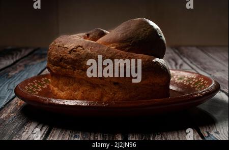 Mexican Oaxaca sweet bread stuffed with chocolate on a mud mexican plate over a rustic wooden table Stock Photo