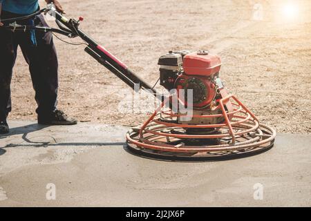 Concrete floor polishing,Construction worker produces the grout and finish wet concrete with a special tool. Float blades. For smoothing and polishing Stock Photo