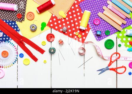 Various fabric, tools and accessories for sewing on a light wooden background. Top view, copy space. Stock Photo
