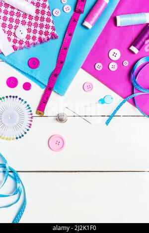 Various fabric, tools and accessories for sewing on a light wooden background. Top view, copy space. Stock Photo