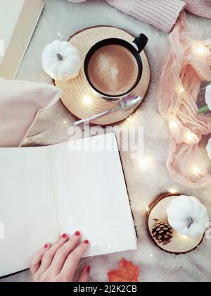 Woman's hand holding open a blank notebook and a cup of coffee with decorations Stock Photo