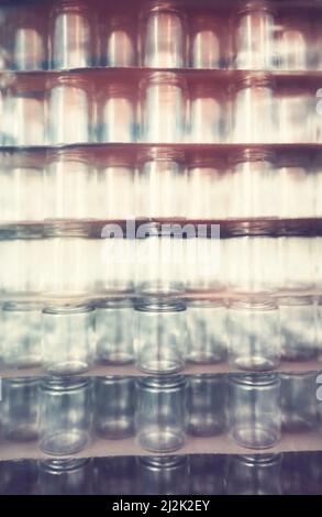 Blurred glass jars covered with plastic, abstract background. Stock Photo