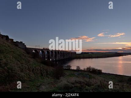 A Virgin Trains east coast intercity 125 crossing the  Royal border bridge, Berwick upon Tweed at sunset. Stock Photo