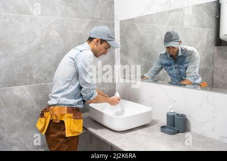 A man is setting the washbasin over the cabinet in the bathroom Stock Photo